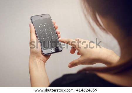 Close up woman hand holding smartphone while entering the passcode.