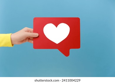 Close up of woman hand holding social media like stick, emoji notification button to follow and subscribe blog or post, popular forum, posing isolated over plain blue color background wall in studio - Powered by Shutterstock