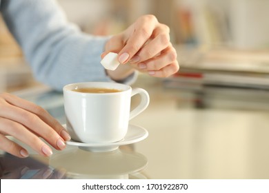 Close Up Of Woman Hand Holding Sugar Cube Over A Coffee Cup On A Desk At Home