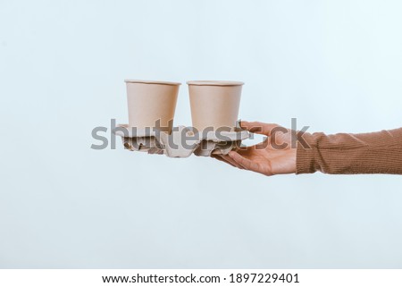 Close up woman hand holding two cup of coffee to take away over white background