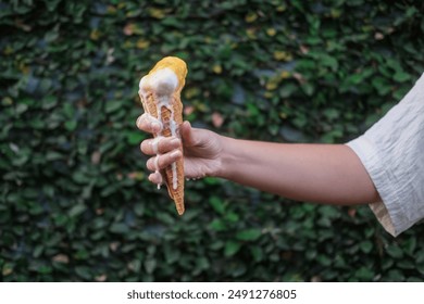 A close up of a woman hand holding a waffle cone with vanilla ice cream, which melts and flows down her hand. Ice cream flows and drips onto your hand. Extreme heat. Summer background. - Powered by Shutterstock