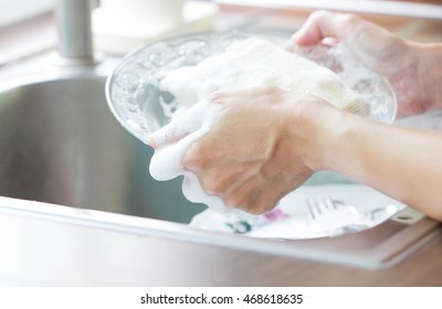 Close Up Woman Hand Holding Yellow Sponge And Washing Saucer With Washed Dishes