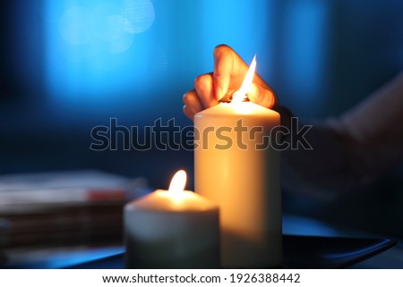 Close up of a woman hand lighting candle in the night at home