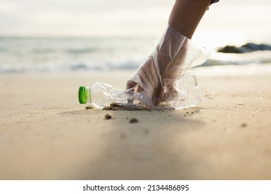 Close up woman hand pick up the plastic bottle on the beach. Female Volunteer clean the trash on the beach make the sea beautiful. World environment day concept. - Powered by Shutterstock