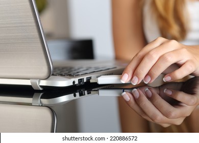 Cerrar una mano de mujer enchufando un pendrive en una laptop en casa