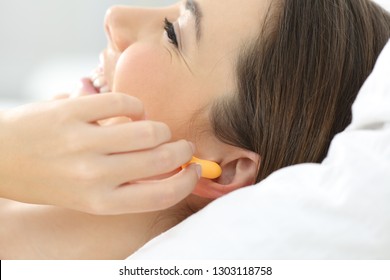 Close Up Of A Woman Hand Putting Ear Plugs To Sleep On A Bed At Home