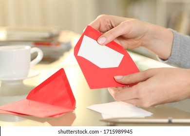 Close up of woman hand putting greeting thank you card on a red envelope sitting on a desk at home