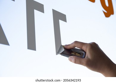 Close Up Of A Woman Hand Removing A Vinyl Sticker From A Window With A Scraper Tool