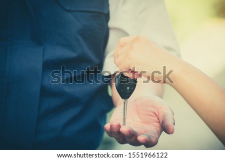 Close up of the woman hand is sending the car keys to the car mechanic. The concept of trust And confidence in using the service