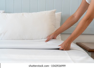 Close up woman hand set up white bed sheet in hotel room, copy space for text. - Shutterstock ID 1542926999