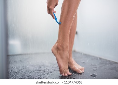Close up woman hand shaving calf while relaxing in shower. Drops of water falling around her
