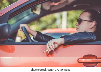 Close Up Of Woman Hand Smoking Cigarette Inside The Car While Driving A Vehicle, Threatening And Dangerous Driving