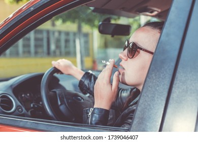 Close Up Of Woman Hand Smoking Cigarette Inside The Car While Driving A Vehicle, Threatening And Dangerous Driving