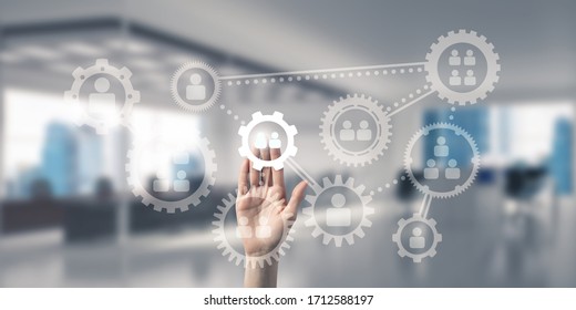 Close of woman hand touching gears on screen with palm and office at background - Shutterstock ID 1712588197