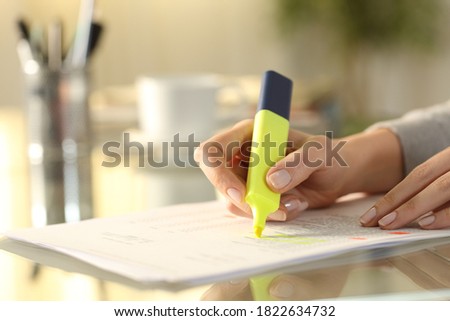 Close up of a woman hand underlining text on document with marker on a desk at home