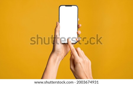 Close up of woman hand using smartphone isolated on orange wall. Female hands showing empty white screen of modern smart phone. Businesswoman holding cellphone and unlocks it with her fingerprint.