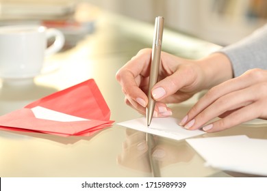 Close up of woman hand writing greeting thank you card sitting on a desk at home