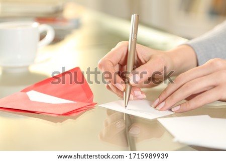 Close up of woman hand writing greeting thank you card sitting on a desk at home
