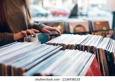 Close up of a woman hands choosing vinyl record in music record shop. Music addict concept. Old school classic concept. Focus on the hands and a vinyl record.