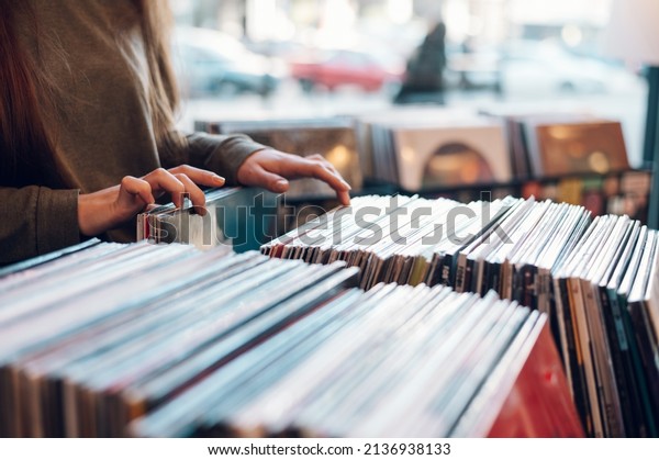 Close up of a woman hands\
choosing vinyl record in music record shop. Music addict concept.\
Old school classic concept. Focus on the hands and a vinyl\
record.
