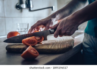Close up of woman hands cutting tomatoes in kitchen on wooden board woman preparing food in kitchen