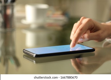 Close up of woman hands entering numbers on a lightened smart phone screen keyboard on a desk at home