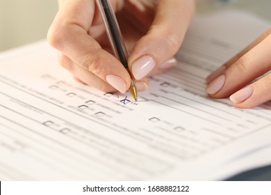 Close up of woman hands filling form crossing yes checkbox on a desk