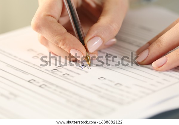 Close up of woman hands filling form crossing yes
checkbox on a desk