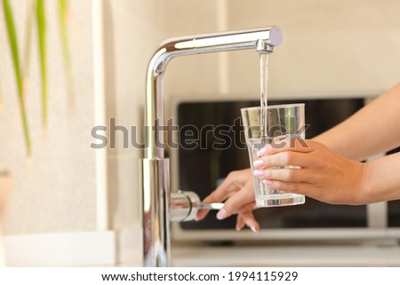 Close up of a woman hands filling a glass of tap water