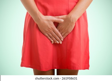 Close up of a woman with hands holding her crotch, isolated in green