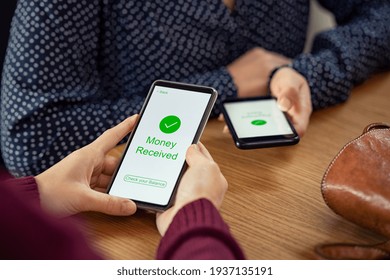 Close up of woman hands holding mobile phone with application to receive money. People holding smart phone and making cashless payment transaction. Smartphone screen displaying money received message. - Shutterstock ID 1937135191