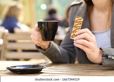 Close Up Of Woman Hands Holding A Snack Cereal Bar And Coffee Cup On A Cafe Terrace