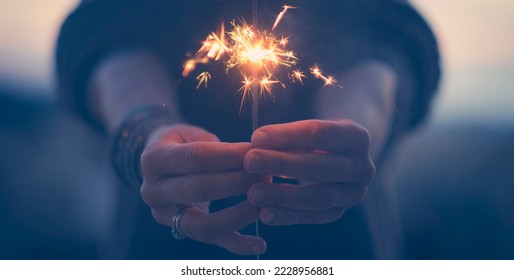 Close up of woman hands holding sparkler light in foreground. Banner image with celebration concept. New year eve and anniversary. Night celebrate people with sparkler in outdoor. Day Dreamer female - Powered by Shutterstock