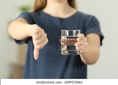 Close up of a woman hands holding a water glass with thumbs down