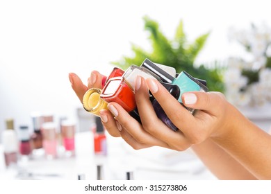 Close up of woman hands with nail polishes of different colors - Shutterstock ID 315273806