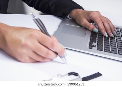Close up of woman hands on the office desk. Working on laptop and writing on paper. - Shutterstock ID 539061253