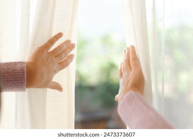 Close up of a woman hands opening curtain of a house window - Powered by Shutterstock