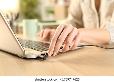 Close up of woman hands plugging battery charger on laptop at home