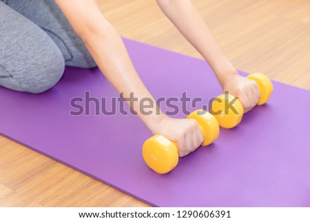 Close up of woman hands pushing dumbbell on training mat, prepare to exercise - cardio workout, healthy concept.