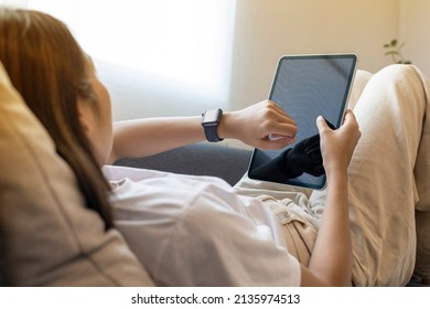 Close up of woman hands setting smart watch and digital tablet lying on sofa at home.  - Powered by Shutterstock