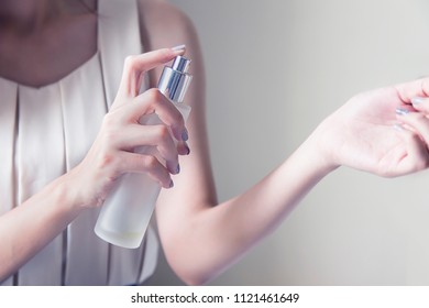 Close Up Of Woman Hands Spraying  Petals From Beautiful Perfume Bottle. Hand And Finger Push On Perfume Or Spray Can. Young Asian Lady Applying Perfume On Her Wrist. 