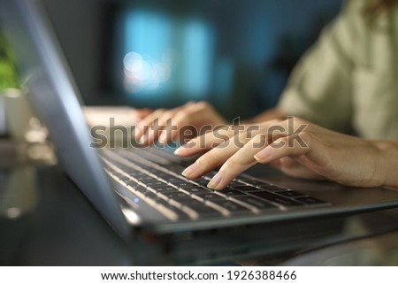 Close up of a woman hands typing on laptop keyboard in the night at home