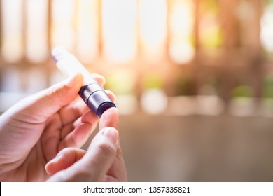 Close up of woman hands using lancet on finger to check blood sugar level by Glucose meter in the morning. Medicine, diabetes, glycemia, health care concept.