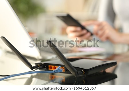 Close up of woman hands using multiple devices with broadband router on foreground