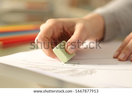 Close up of woman hands using rubber erasing pencil drawing on a desk at home