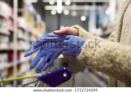 Close up woman hands wearing blue latex gloves at shopping mall near food trolley. Step of prevention coronavirus infection spread in quarantine, protection measure self hygiene, selective focus