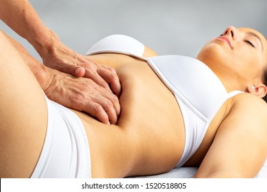 Close up of woman having intestinal obstruction therapy. Girl lying on spa bed with hands massaging abdomen.