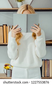 Close Up Of Woman Hiding Face Behind Book