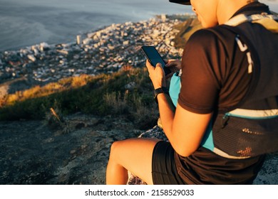 Close Up Woman Hiker In Sportsclothes Checking Smartphone While Sitting On The Top Of The Mountain At Sunset