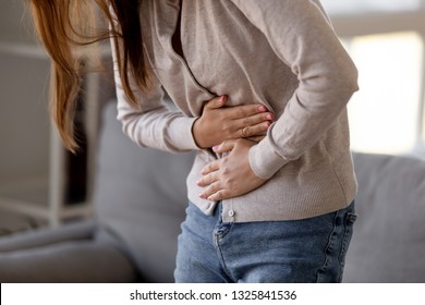 Close up woman holding belly, feeling discomfort, health problem concept, unhappy girl standing at home, suffering from stomachache, food poisoning, gastritis, abdominal pain, menstrual period